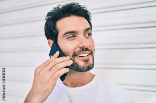 Young hispanic man smiling happy talking on the smartphone at city.