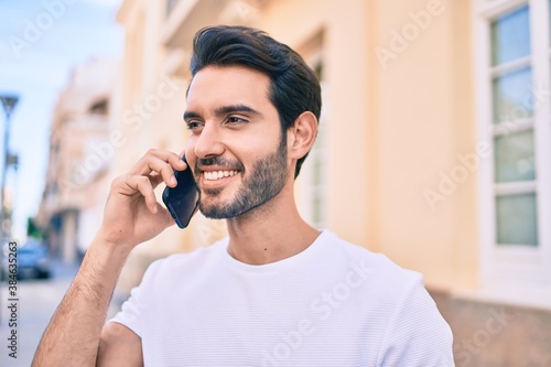 Young hispanic man smiling happy talking on the smartphone at city.