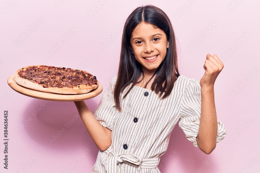 Beautiful child girl holding italian pizza screaming proud, celebrating victory and success very excited with raised arms Beautiful child girl holding italian pizza screaming proud, celebrating victory and success very excited with raised arms
