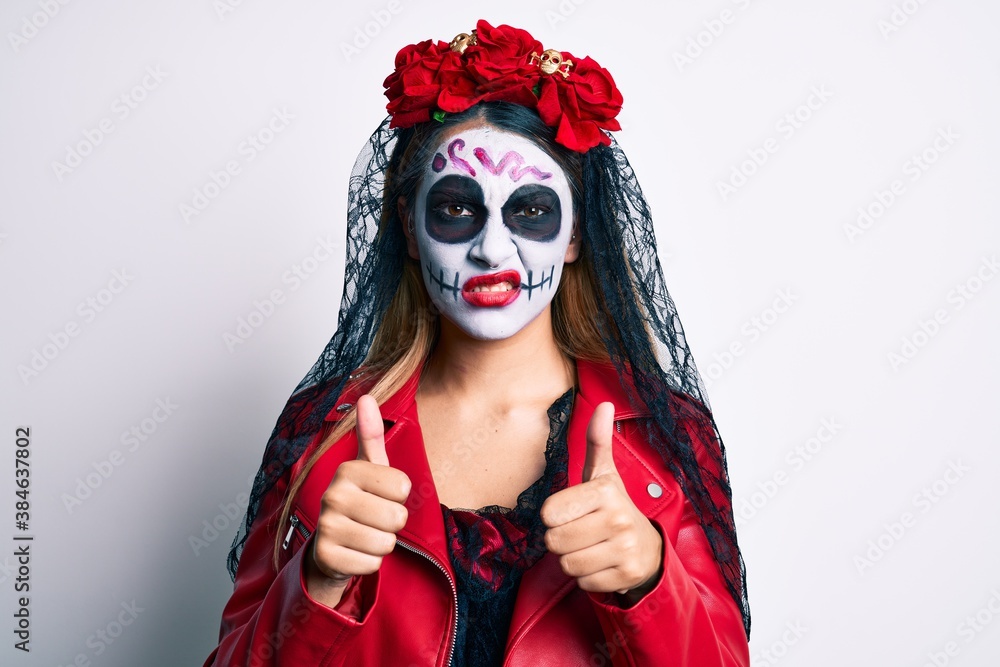 Woman wearing day of the dead costume with thumbs up doing ok sign clueless and confused expression. doubt concept.