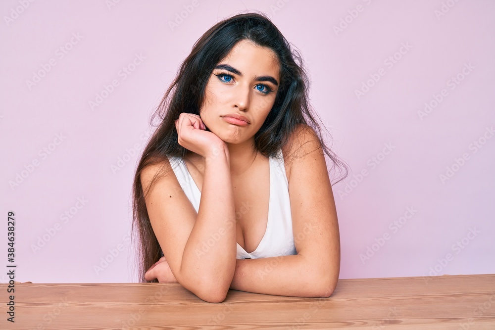 Brunette teenager girl wearing casual clothes sitting on the table thinking looking tired and bored with depression problems with crossed arms. Brunette teenager girl wearing casual clothes sitting on the table thinking looking tired and bored with depression problems with crossed arms.