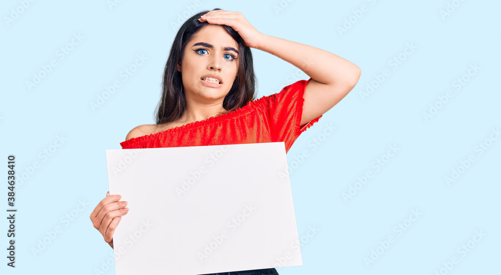 Brunette teenager girl holding blank empty banner stressed and frustrated with hand on head, surprised and angry face Brunette teenager girl holding blank empty banner stressed and frustrated with hand on head, surprised and angry face