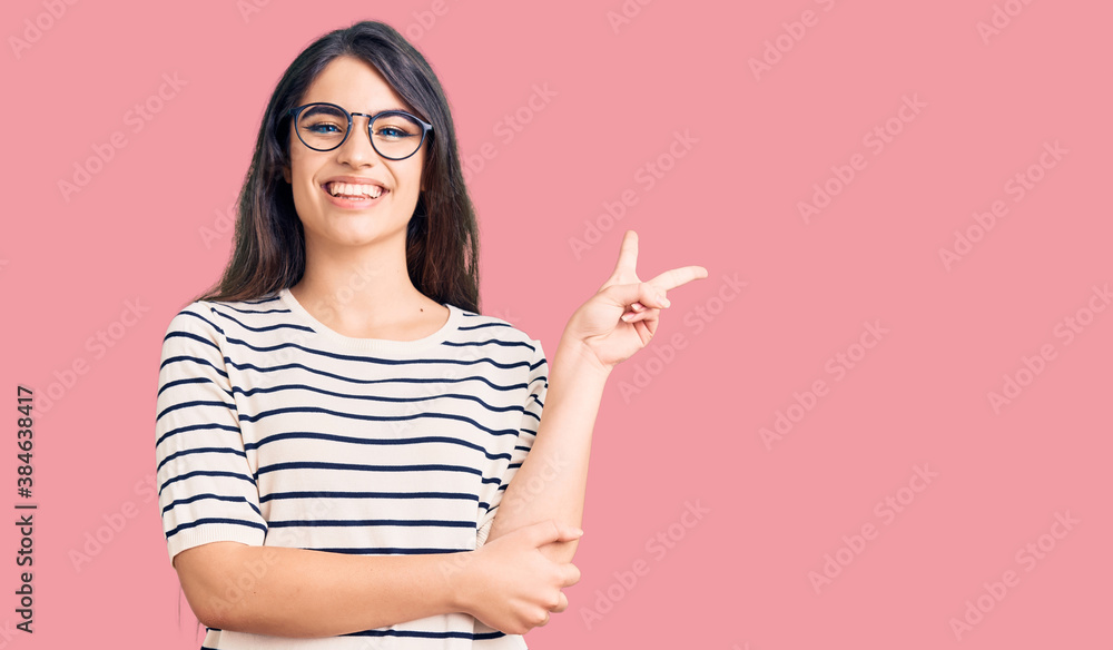 Brunette teenager girl wearing casual clothes and glasses smiling with happy face winking at the camera doing victory sign. number two. Brunette teenager girl wearing casual clothes and glasses smiling with happy face winking at the camera doing victory sign. number two.