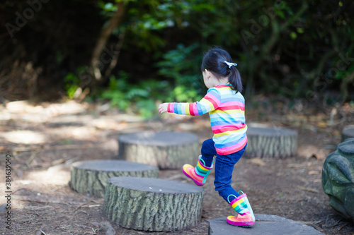 young girl jumping between the timber in the forest park