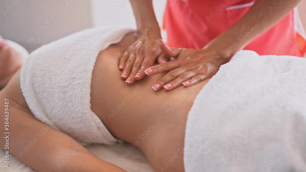 Woman make a belly massage in light procedure room. Anti-cellulite massage, diastasis. Faces are not recognizable Woman make a belly massage in light procedure room. Anti-cellulite massage, diastasis. Faces are not recognizable