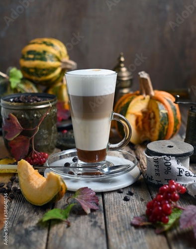 Pumpkin spice latte with whipped cream and cinnamon in glass on rustic wooden background. Selective focus.