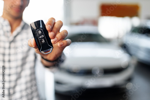 Male hand showing car keys against new luxury car