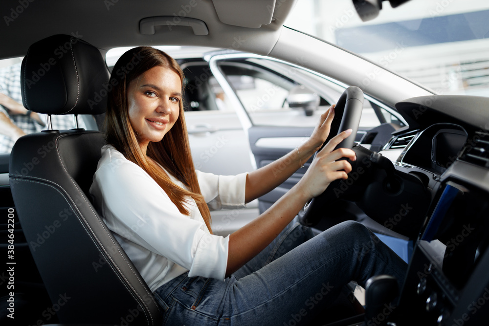 Young attractive woman looking for a new car in a showroom Young attractive woman looking for a new car in a showroom