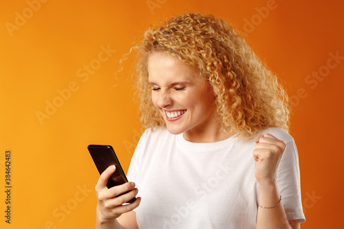 Young blonde curly girl using her smartphone