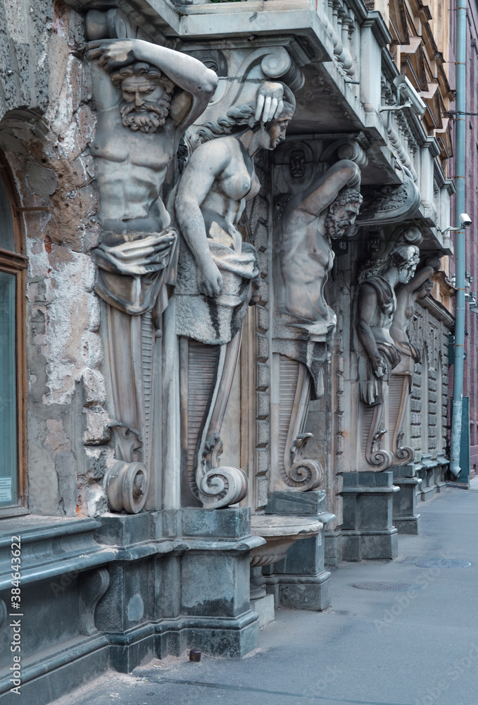 Bolshaya Morskaya street 43, Saint Petersburg, Russia, 11.10.2020. Bearded old Atlanteans, women sculptures keep balcony of facade, wall of historical building. House of Demidov. Demidov's mansion