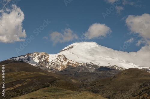 snowy landscape in Cayambe, with clear skies and several mountains around, photo in the day