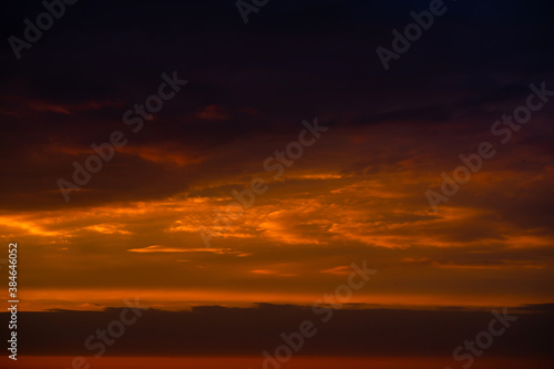 Heavy cloudy sky at sunset. Orange line of light between black clouds. A landscape of beautiful nature