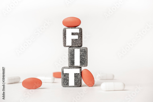 a group of white and red pills and cubes with the word fit on them, white background. Concept carehealth, treatment, therapy. photo