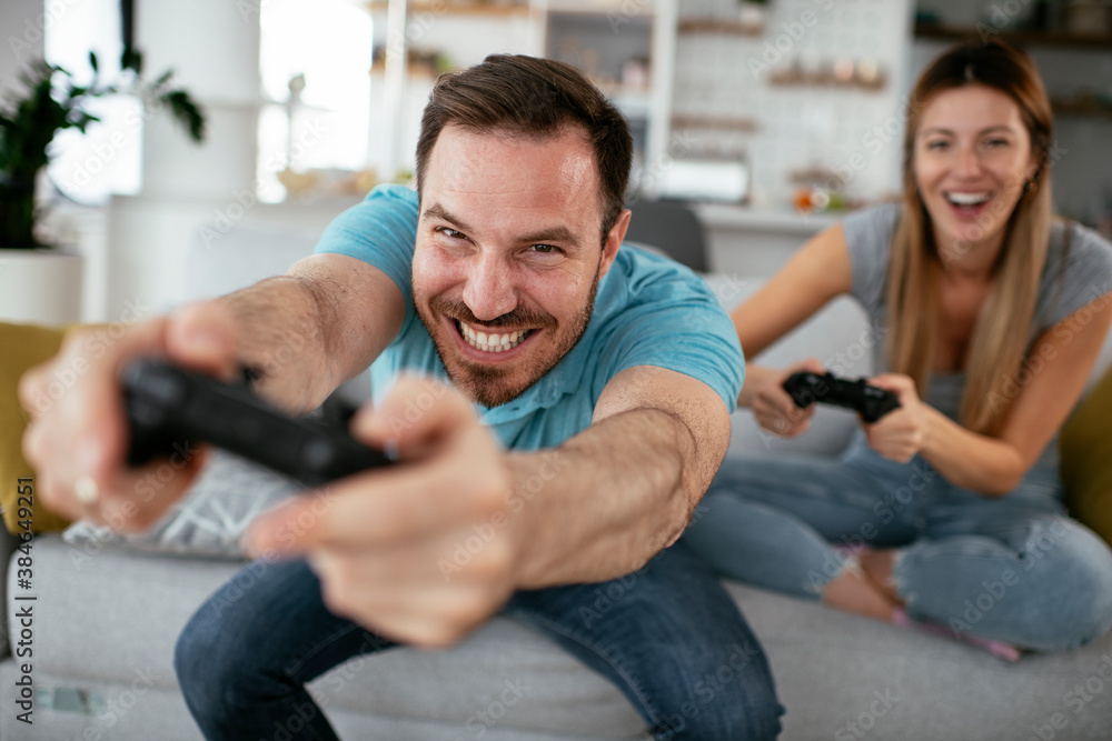 Husband and wife playing video game with joysticks in living room. Loving couple are playing video games at home. Husband and wife playing video game with joysticks in living room. Loving couple are playing video games at home.