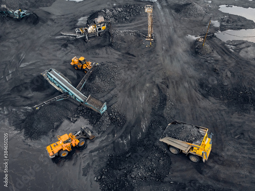 Transporting coal on yellow large dump truck. Open pit mine industry Top aerial view