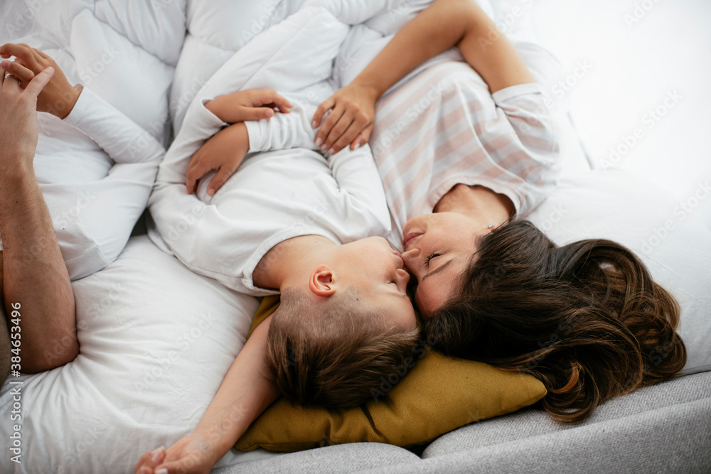 Young family enjoying in bed. Happy parents with sons relaxing in bed.. Young family enjoying in bed. Happy parents with sons relaxing in bed..