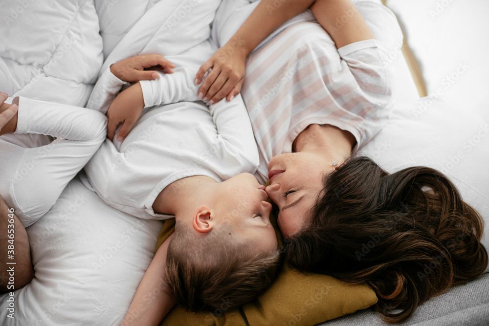 Young family enjoying in bed. Happy parents with sons relaxing in bed..