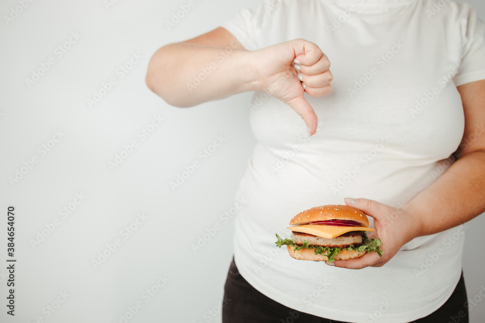 Overweight woman with hamburger and thumb down Overweight woman with hamburger and thumb down