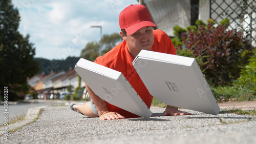 Valokuva CLOSE UP: Courier trips and falls to asphalt pavement along with two pizza boxes