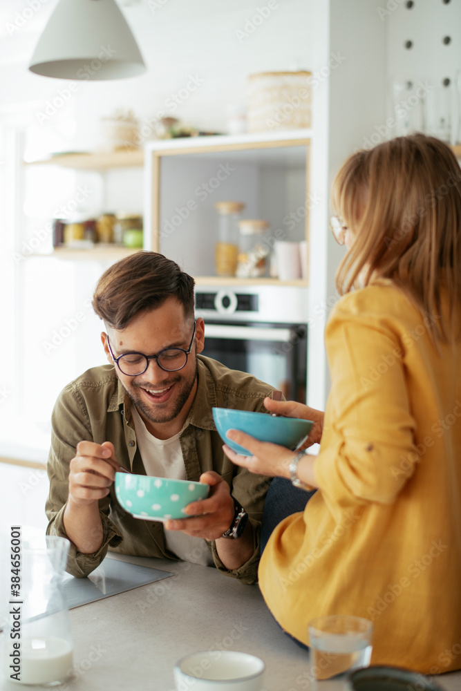 Obraz premium Young couple eating breakfast at home. Loving couple enjoying in the kitchen..