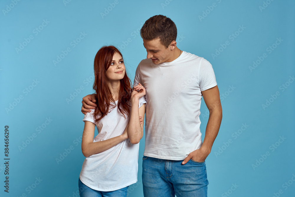 Fototapeta premium enamored man and woman in jeans and a T-shirt on a blue background hug each other and have fun