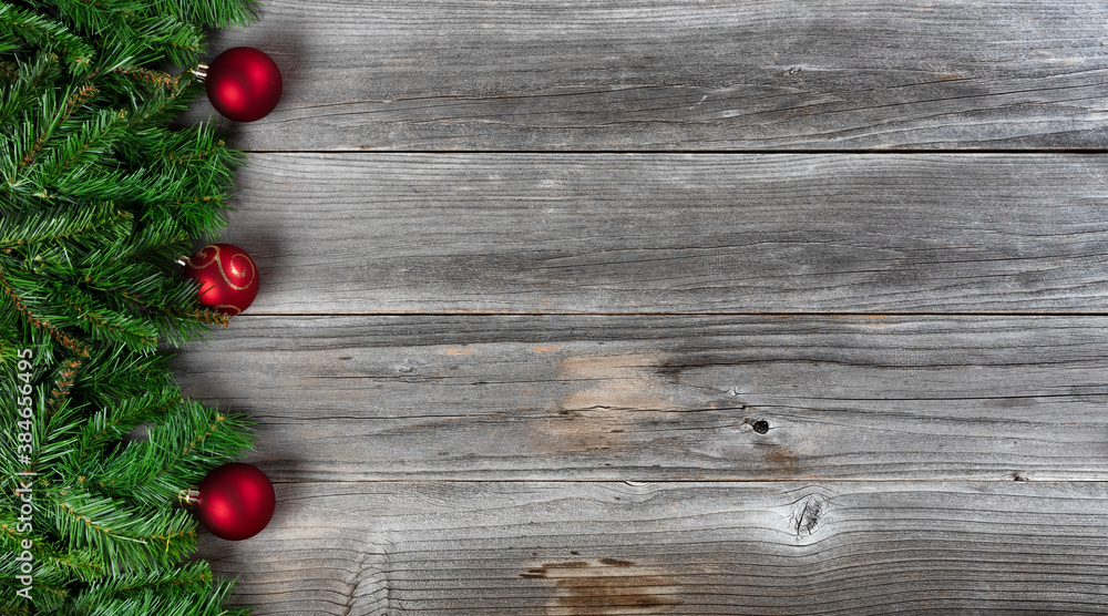 Merry Christmas and Happy New Year theme consisting of fir branches and red ball ornaments on left side of rustic wooden boards Merry Christmas and Happy New Year theme consisting of fir branches and red ball ornaments on left side of rustic wooden boards