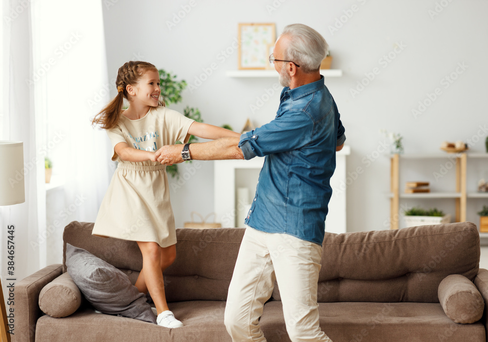 Fototapeta premium Grandfather dancing with granddaughter at home.
