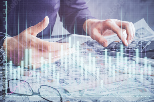 Double exposure of man's hands holding and using a digital device and forex graph drawing. Financial market concept.