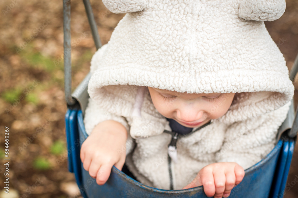 baby looking down on a swing with hooded sweater baby looking down on a swing with hooded sweater