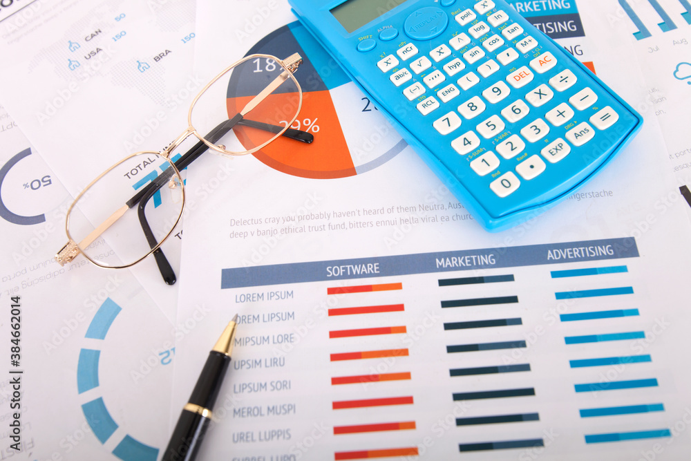 Fototapeta premium Calculator and signature pen and a pair of glasses on financial documents
