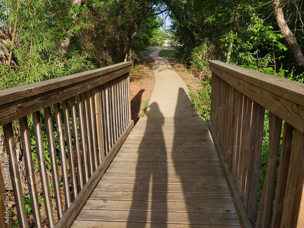 Close up of a wooden footbridge in a forest park with shadows of people Close up of a wooden footbridge in a forest park with shadows of people