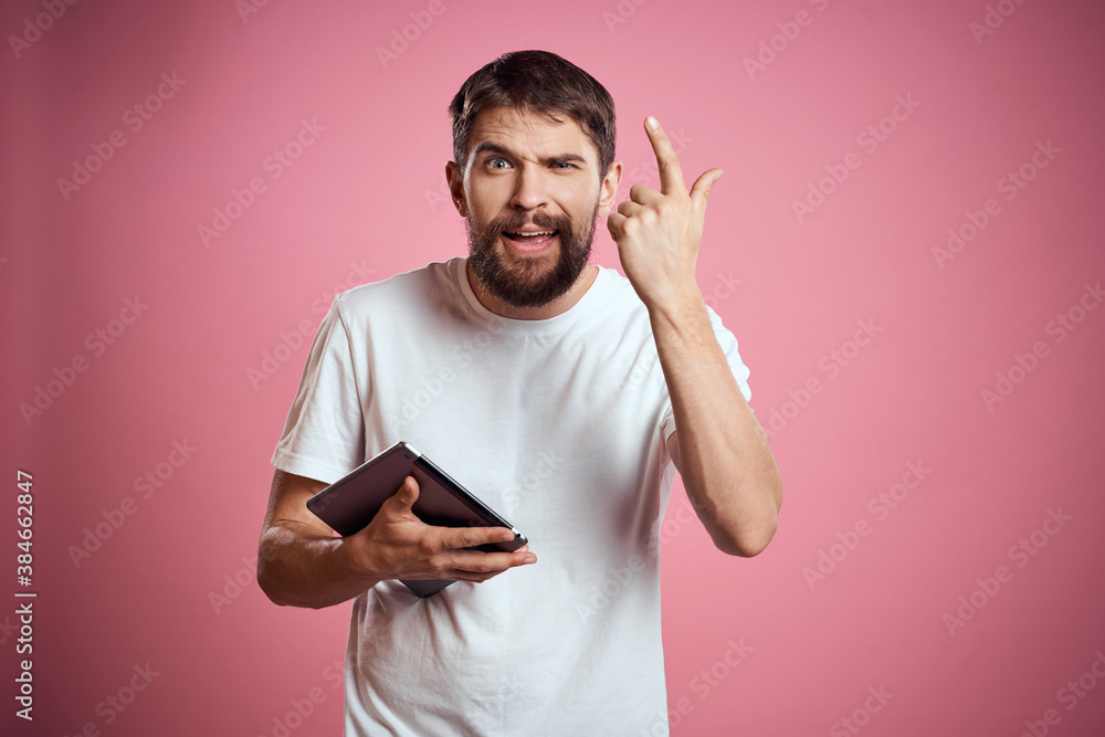 Man advertises a tablet on a pink background codes Space cropped view of emotions white t-shirt model new technologies Man advertises a tablet on a pink background codes Space cropped view of emotions white t-shirt model new technologies