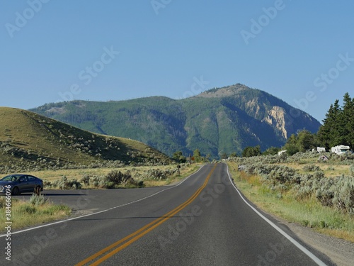 Wyoming, USA--July 2018: Paved road with vehicles parked on the sides near Mammoth Hot Springs at Yellowstone National Park.