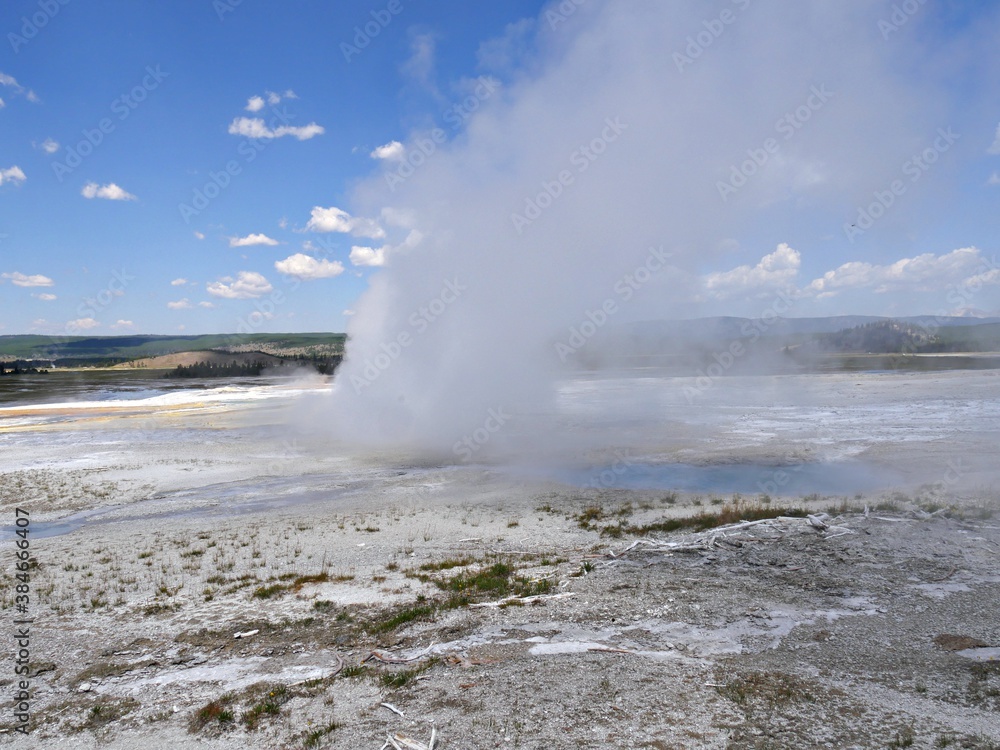 Wide shot of Clepsydra Geyser with steam shooting up at the Lower Geyser Basin, Yellowstone National Park.