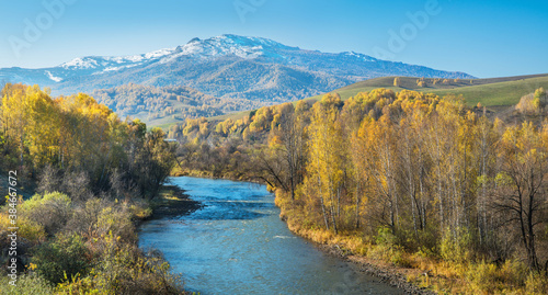 River  forested banks and a snow-capped peak. Sunny autumn day.