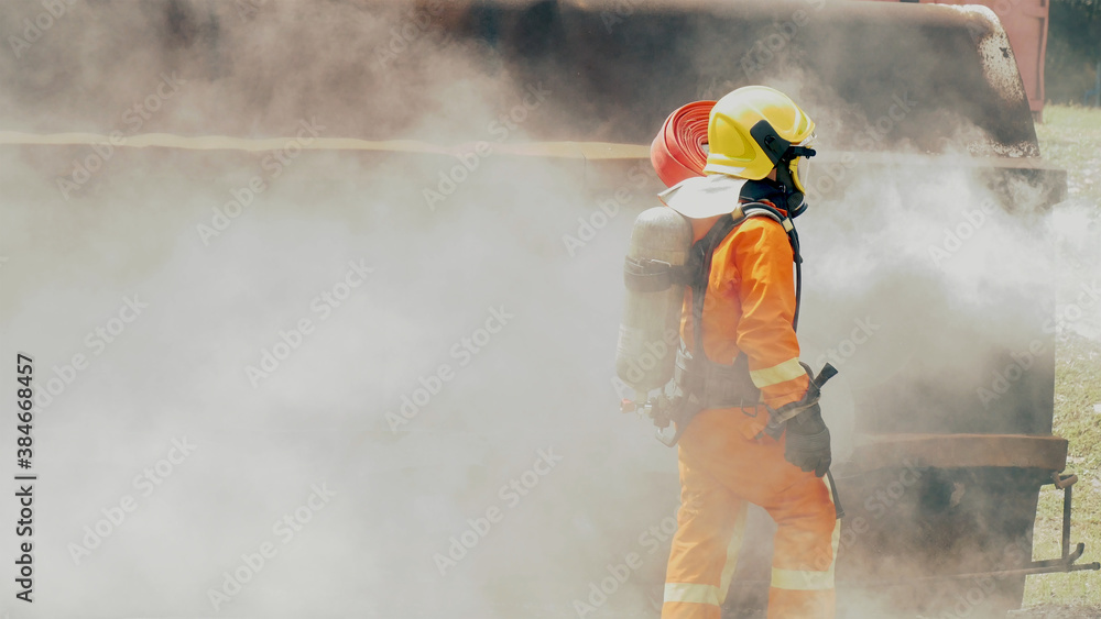 Fototapeta premium Firefighter fighting with flame using fire hose chemical water foam spray engine. Fireman wear hard hat, body safe suit uniform for protection. Rescue training in fire fighting extinguisher