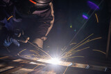 The welder is welding the parts of the iron door. The person working on a welder using an electric welding machine.