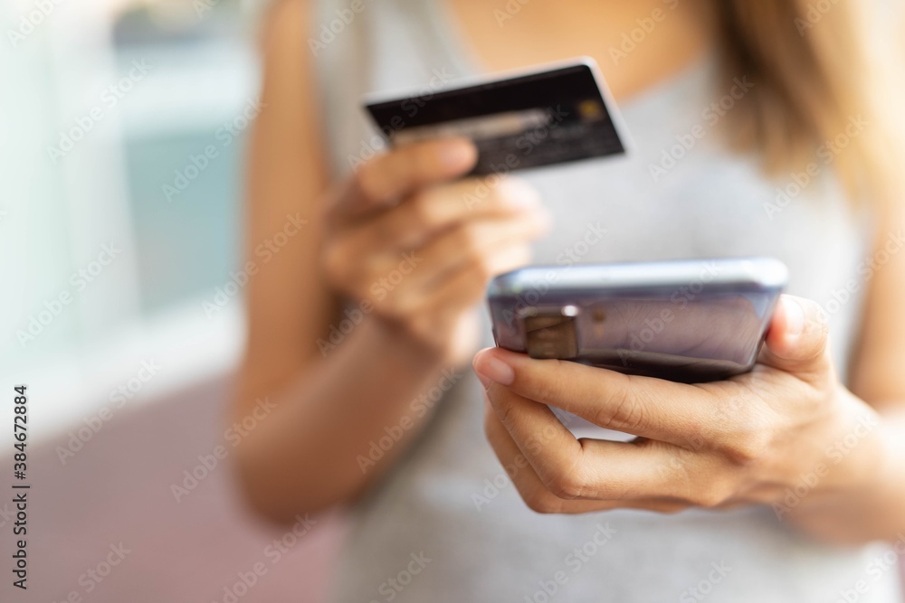 A woman holding a phone and dialing a credit card code online to payment for shopping online. A woman holding a phone and dialing a credit card code online to payment for shopping online.