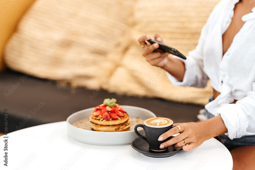 Woman taking a photo of breakfast with smartphone. Morning time.