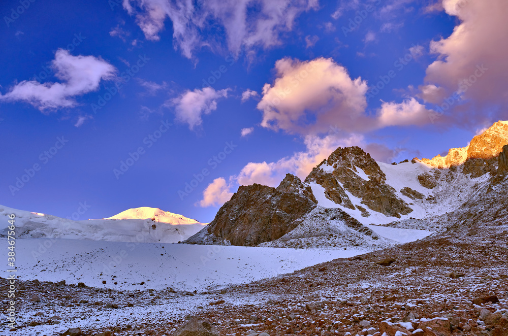 Mountain peaks illuminated by the first rays of the sun; picturesque sunrise in the mountains