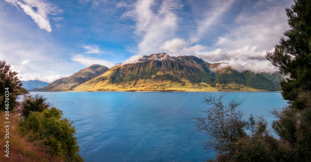 Lake Wanaka alpine Panorama close to sunset with mountain peaks in the distance in Mount Aspiring National Park, Otago Region, New Zealand, Southern Alps.