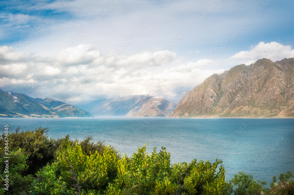 Sunny but slightly foggy mountain range close up view at Lake Hawea in Mount Aspiring National Park, Otago Region, New Zealand, Southern Alps.