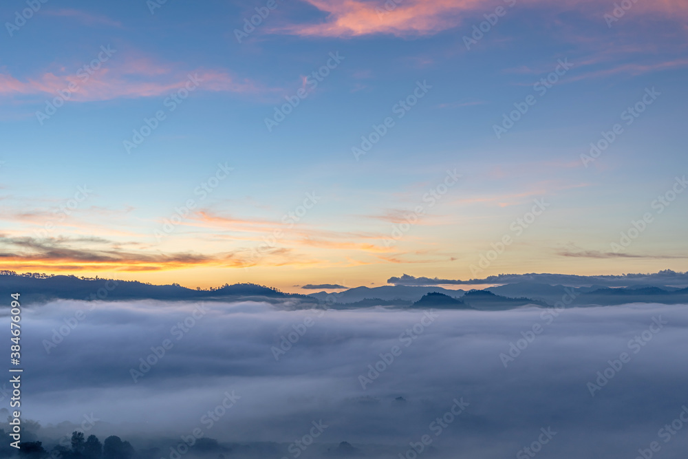 Autumn foggy mountains landscape with colorful sky in morning