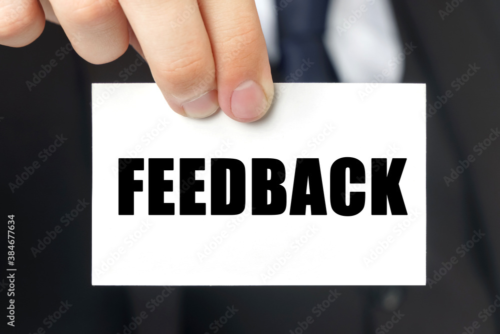 Businessman shows a card with the text FEEDBACK Businessman shows a card with the text FEEDBACK