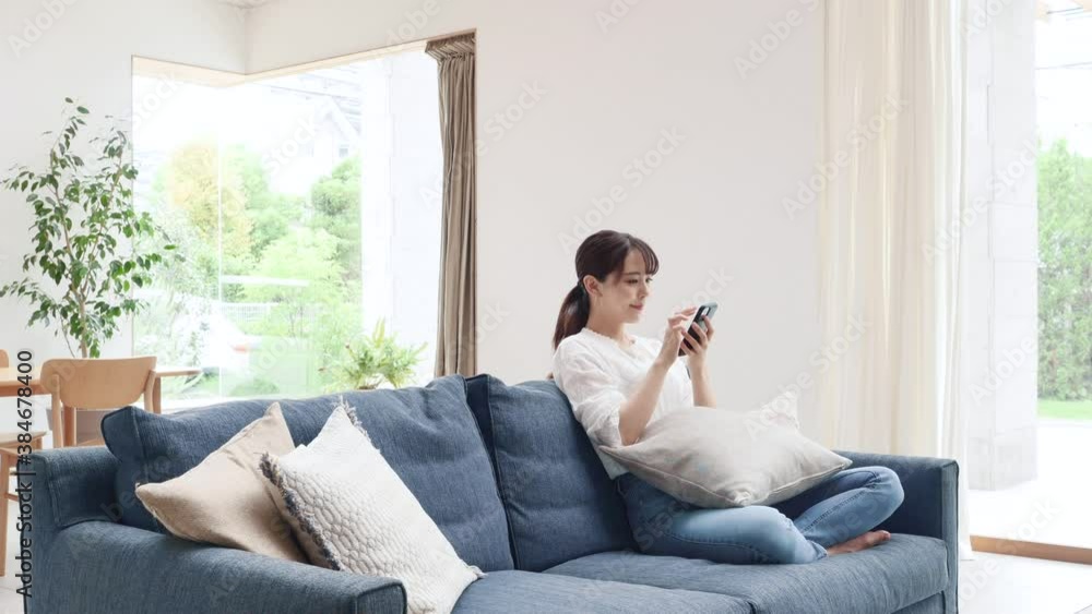 部屋でスマートフォンを使う女性 部屋でスマートフォンを使う女性