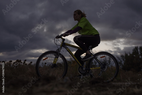 Sport woman bicycling against dramatic sky background