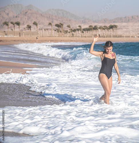 Cheerful woman in a bathing suit runs by the sea
