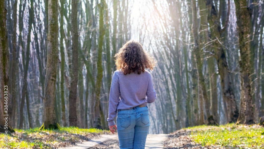 Young girl walking in the spring forest on a sunny day Young girl walking in the spring forest on a sunny day