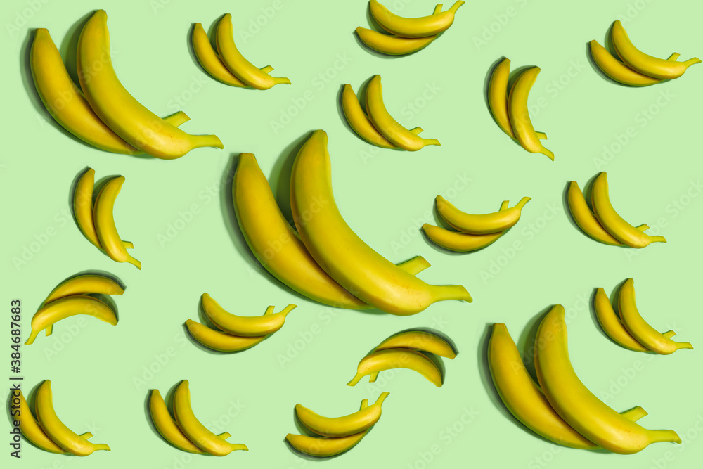 Fruit pattern. Repetition of whole bananas of different sizes on a light green background. Interesting fruit pattern made from natural fruits. Horizontal. The concept of healthy food and vegetarianism Fruit pattern. Repetition of whole bananas of different sizes on a light green background. Interesting fruit pattern made from natural fruits. Horizontal. The concept of healthy food and vegetarianism