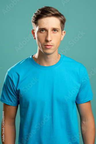 Confident male portrait. Healthy lifestyle. Masculine power. Young attractive serious man in t-shirt looking at camera isolated on blue.